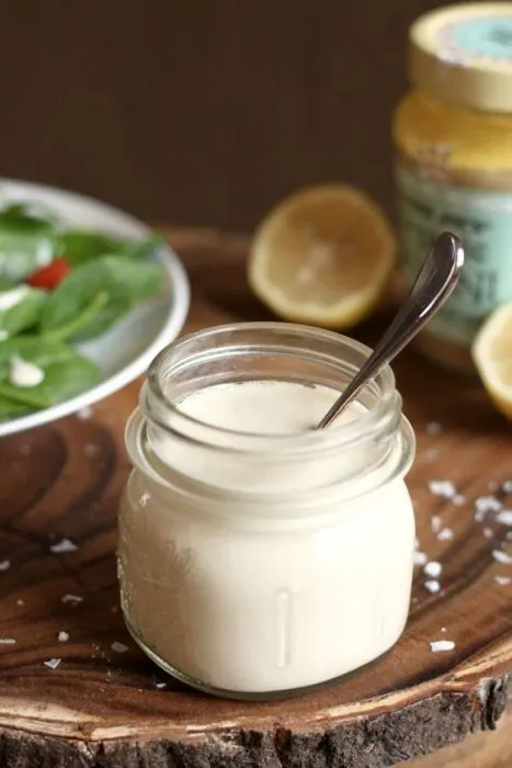 lemon tahini sauce in small container with salad in background