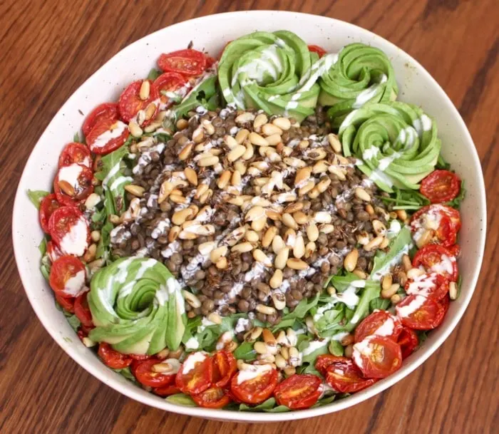 vegan arugula lentil salad with cumin toasted pine nuts, oven roasted tomatoes, and avocados