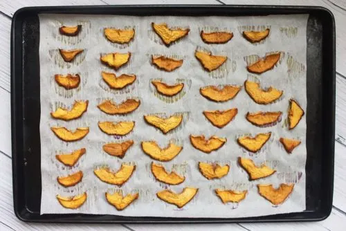 finished peach chips on a parchment lined baking sheet