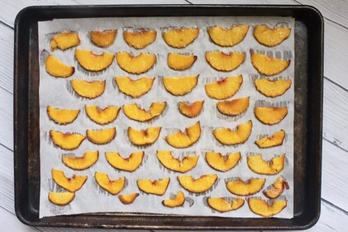 thinly slice peaches on a parchment lined baking sheet