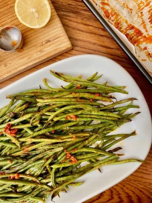 Harissa roasted green beans served on a white serving platter