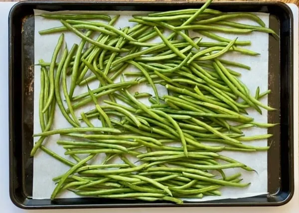 washed green beans on a parchment lined baking sheet