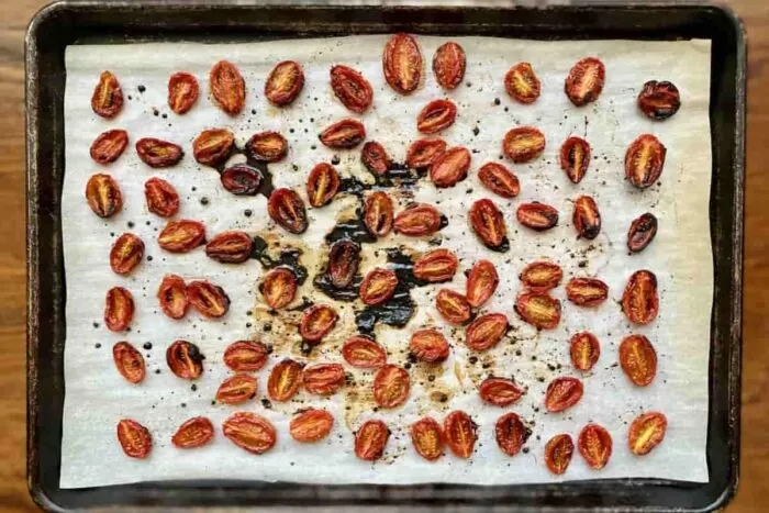 Roasted cherry tomatoes on a parchment lined baking sheet